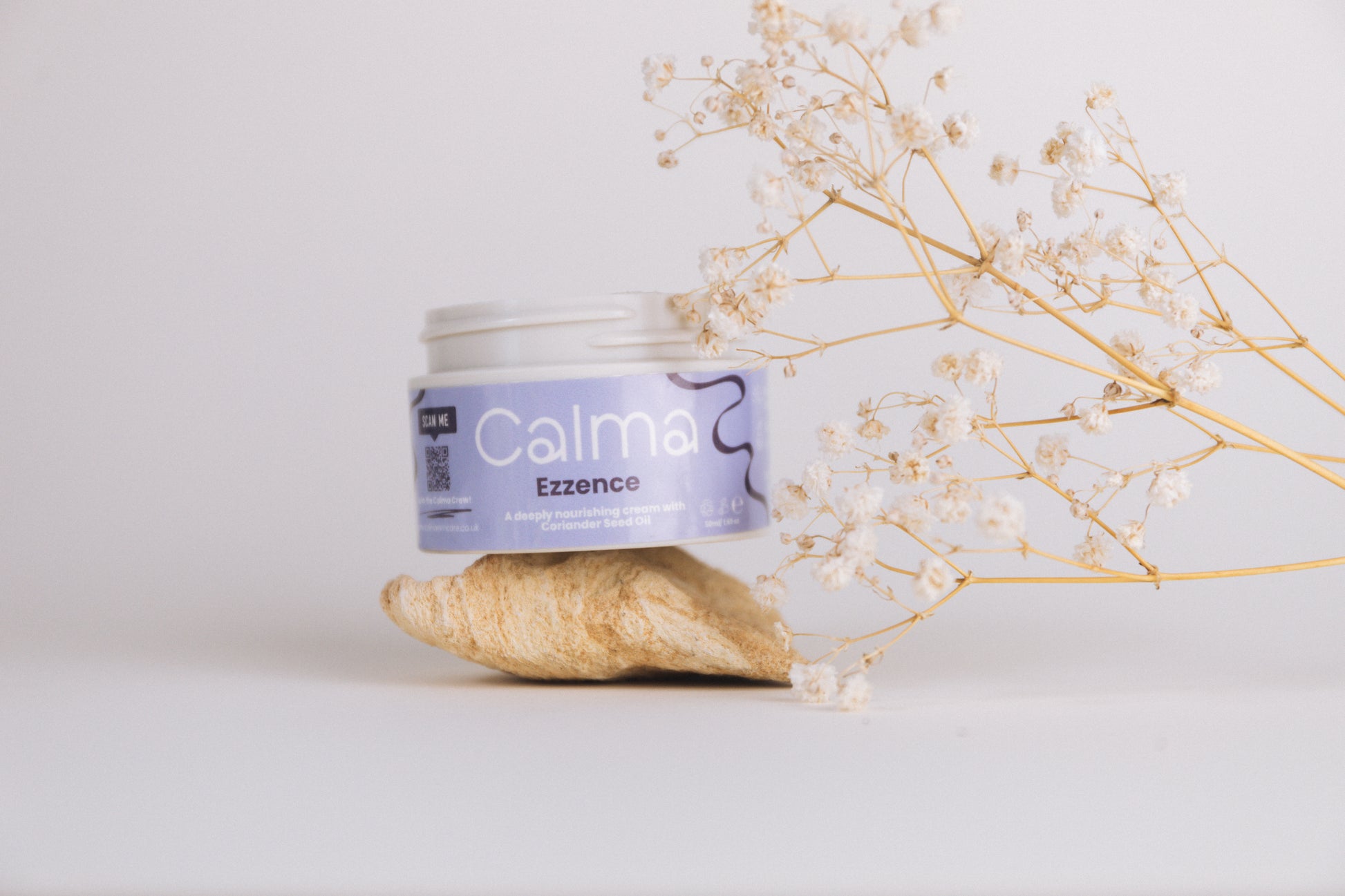 Jar of Calma Essence with dried flowers on a light background